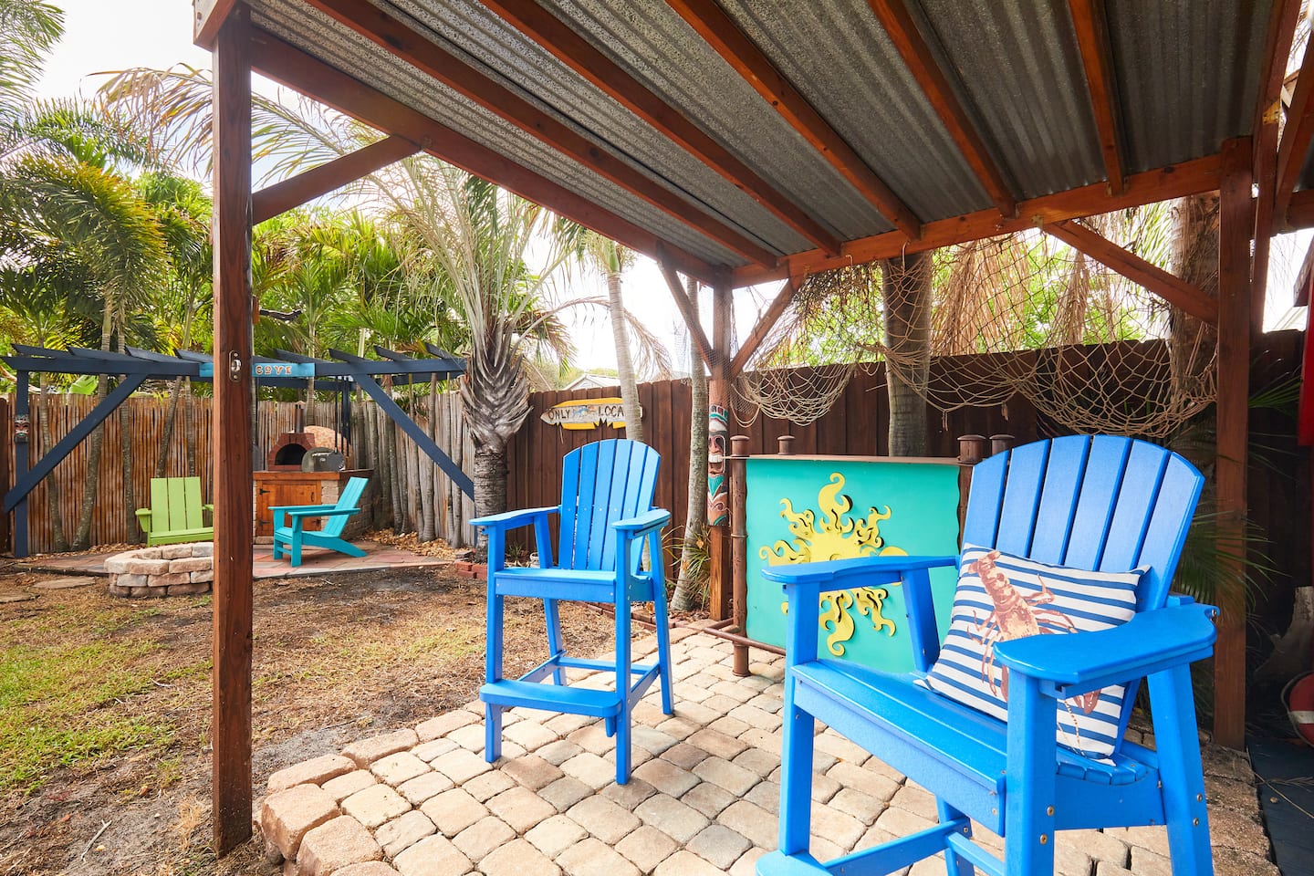 A covered bar with bright blue high chairs, a painted octopus mural and fishing net on the wall.
